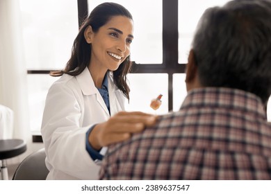 Positive beautiful geriatric medical therapist woman seeing older grey haired patient, touching shoulder od man, giving empathy, support, consultation after treatment, healthcare checkup
