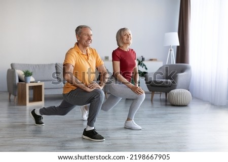 Positive beautiful mature couple having workout at home, cheerful senior man and woman in sportswear exercising together, looking at copy space and smiling, full length shot. Sport for seniors