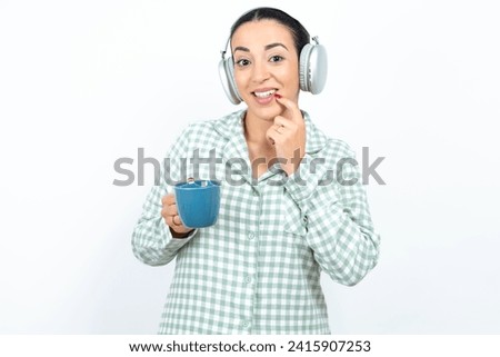 Positive Beautiful young woman wearing green plaid pyjama advert promo touch finger teeth