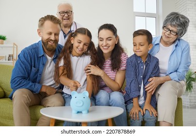 Positive Big Family Throws Coins Into Piggy Bank Collecting Money For Car, Travel And Education. Multi Generations Family Is Having Fun At Home Collecting Money In Piggy Bank In Shape Of Pig.