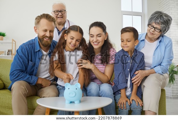Positive big family throws coins into piggy bank\
collecting money for car, travel and education. Multi generations\
family is having fun at home collecting money in piggy bank in\
shape of pig.
