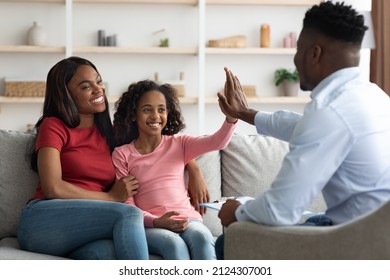 Positive Black Mother And Daughter Teenager At The Appointment With Male Psychologist, Happy African American Girl Giving Psychotherapist High Five, Clinic Interior, Family Therapy Session Concept