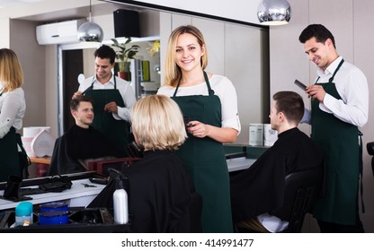 Positive Blonde Cuts Hair Of Senior Woman At Salon