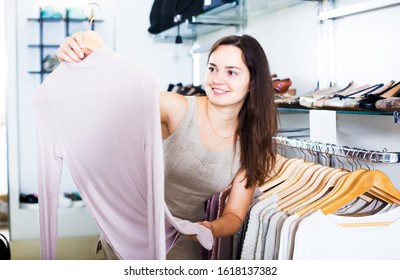 Positive Brunette Girl Selecting Basic Blouse In Apparel Store