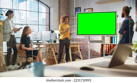 Positive Businesswoman Leading a Team Meeting in Creative Office Conference Room. Excited Multiethnic Woman Showing Presentation on Green Screen Mock Up Chroma Key Monitor. - Powered by Shutterstock