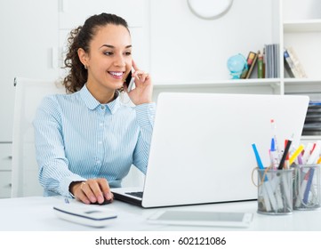 Positive businesswoman talking on mobile phone in modern office