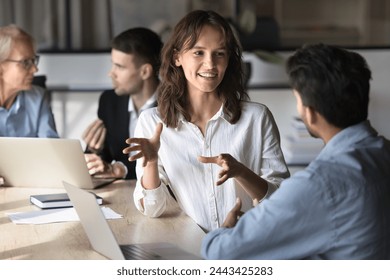 Positive Caucasian project manager woman talking to Indian coworker, business partner at office meeting, discussing collaboration, moving hands, smiling, explaining ideas, planning work process - Powered by Shutterstock