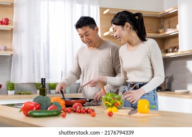 Positive Chinese Family Young Wife And Middle Aged Husband Making Food Together At Home, Happy Asian Couple Cooking Healthy Delicious Food, Using Only Organic Ingredients, Copy Space