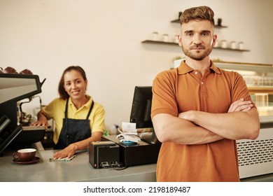 Positive Coffeeshop Owner Standing At Counter With Arms Crossed