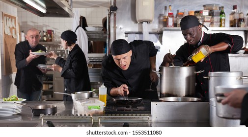 Positive cooks in process of working in kitchen of restaurant