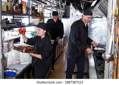 Positive cooks in process of working in kitchen of restaurant