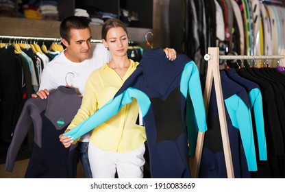 Positive Couple Choosing Diving Suit In Clothing Store