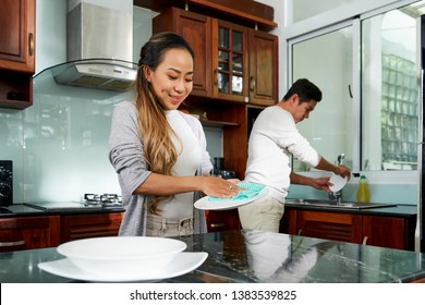 Positive couple washing up after dinner