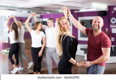 Positive couples enjoying of partner dance and smiling