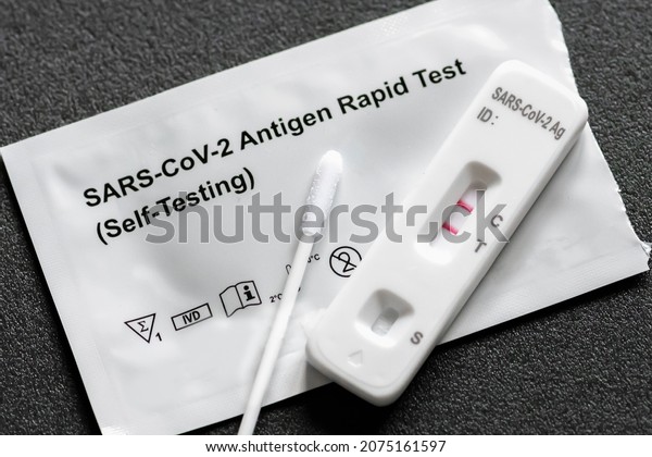 Positive Covid-19, SARS‑CoV‑2 antigen test kit for\
self testing, one step coronavirus antigen rapid test, saliva swab,\
1 test box, close up
