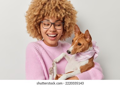 Positive curly haired female pet owner poses with pedigree dog smiles gladfully have good time together pose for making photo stand against white studio wall. Pets people and friendship concept - Shutterstock ID 2220335143