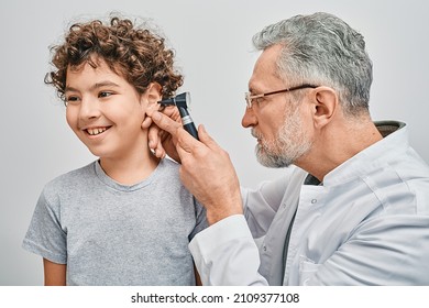 Positive curly male child while ear examining at hearing clinic. ENT doctor checking boy ear using otoscope - Powered by Shutterstock