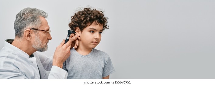 Positive Curly Male Child While Ear Examining With Audiologist. ENT Doctor Checking Boy Ear Using Otoscope