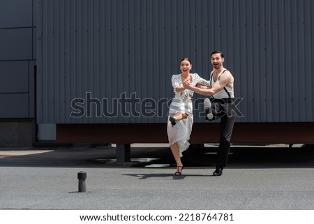 Positive dancers looking away while performing choreography on rooftop 