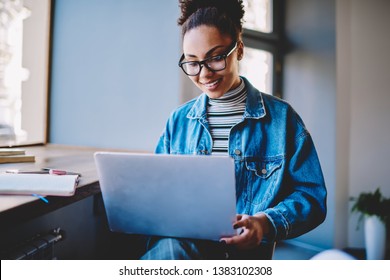 Positive Dark Skinned Female Student Enjoying Time For Online Shopping During Leisure Time For Herself, Happy Teenager In Optical Eyewear Watching Funny Videos On Popular Websites In Internet Space