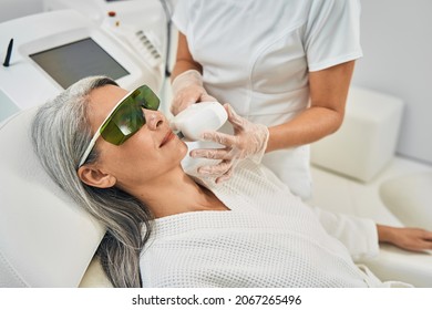 Positive delighted grey-haired female looking at her cosmetologist