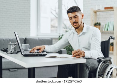 Positive Disabled Young Man In Wheelchair Working In Office