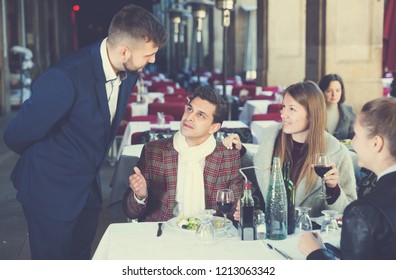 Positive Elegant Company Of Three Sitting On Terrace Restaurant, Talking With Manager
