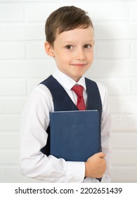 Positive Elementary School Nerd Student Holding Textbook And Looking At You On Light Background