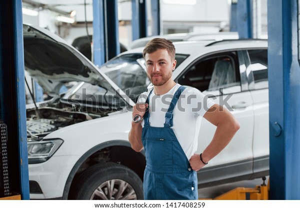Positive emotions. Employee in the blue\
colored uniform works in the automobile\
salon.