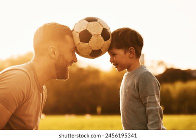 Positive emotions, holding soccer ball by heads. Happy father with son are having fun on the field at summertime. - Powered by Shutterstock