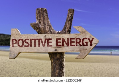 Positive Energy wooden sign with a beach on background