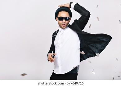 Positive excited handsome guy in suit, hat, black sunglasses having fun on white background. Listening to music through headphones, dancing, singing, celebrating party, happiness - Powered by Shutterstock