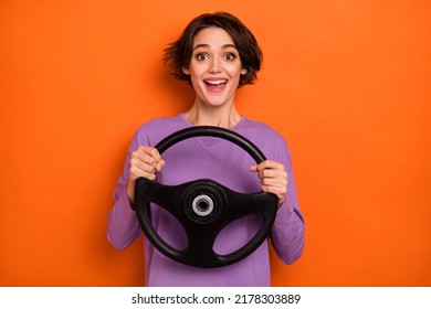 Positive excited lady hold wheel drive fast have good mood isolated on orange color background