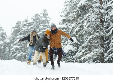 Positive excited young friends in warm clothing running over winter hill while having fun in forest - Shutterstock ID 1208877850