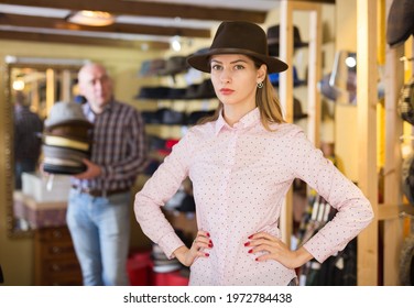 Positive female customer trying on new fedora hat during shopping with male sales assistant - Powered by Shutterstock