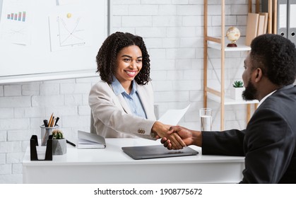 Positive female personnel manager and black job applicant shaking hands before employment interview at company office. Specialist headhunter communicating with vacancy candidate