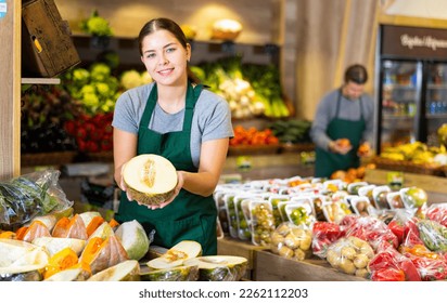 Positive female seller with half of melon on the supermarket - Powered by Shutterstock