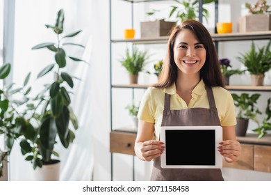Positive florist holding digital tablet in flower shop