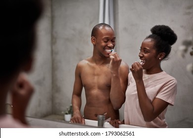 positive friendly african couple in bathroom, beautiful woman and handsome shirtless guy begin their morning together, brush teeth and look at each other - Powered by Shutterstock