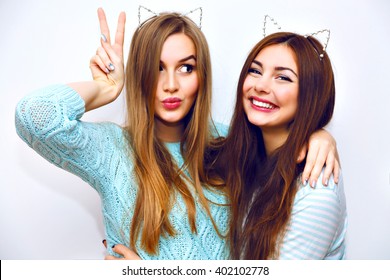 Positive friends portrait of two happy sister girls making selfie, sure funny faces, grimaces, joy, emotions, casual style, pastel colors, white wall. crazy funny woman.