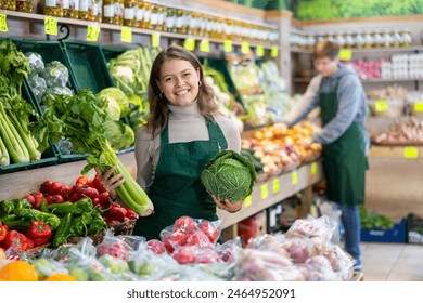 Positive girl seller with cabbage in her hands in the grocery department of the supermarket - Powered by Shutterstock