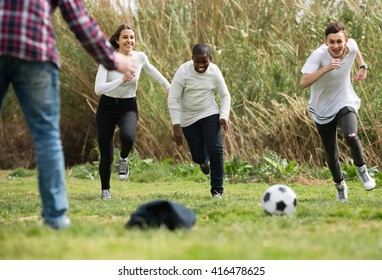positive girl and three boys playing football in spring park and smiling - Shutterstock ID 416478625