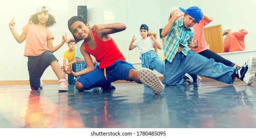Positive girls and boys with female teacher posing in dance studio during hip hop class