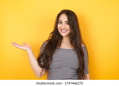 Positive glad female says: wow how exciting it is, has amazed expression, shows something on blank space with open hand over isolated background. Advertisement concept.