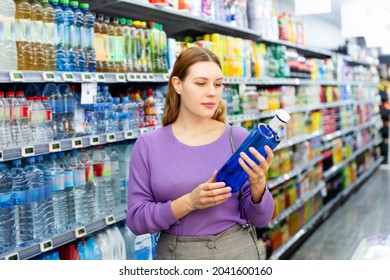 Positive glad pleasant female in the shop want to buying bottle with water