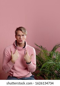 Positive Guy In Coral Hoodie On Pink Background. Conversation And Gestures, Pointing The Finger At Yourself