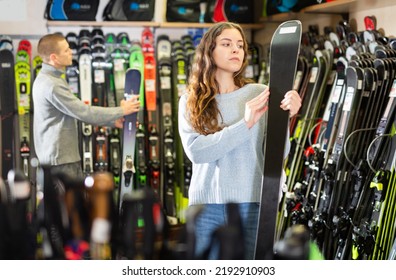 Positive Guy And Girl Are Choosing Skis In A Sports Equipment Store