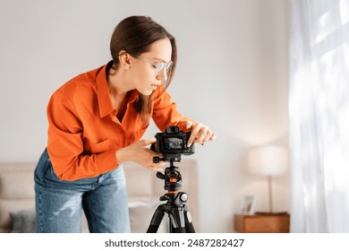 Positive happy woman adjusting camera on tripod, smiling, preparing for online conference from home. People and technologies concept - Powered by Shutterstock