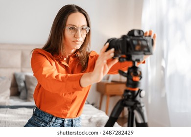 Positive happy woman adjusting camera on tripod, smiling, preparing for online conference from home. People and technologies concept - Powered by Shutterstock