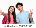 Positive high school pupils students teenagers classmates boy girl friends social media blogger in casual with bags takes selfie photo holding mobile phone doing peace victory on white background.